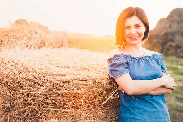 Güzel bir kadın samanlıkta gülümsüyor.