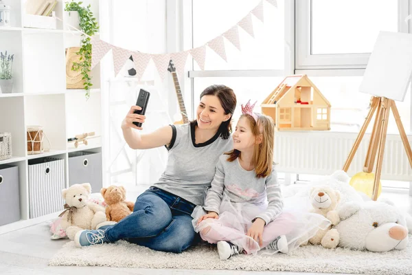 Mère souriante avec fille prenant selfie — Photo