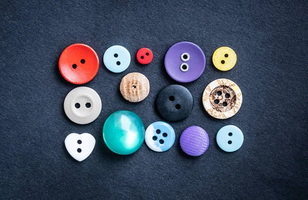 Koyu renk kumaşın üzerinde düğmeler dikiyorum.