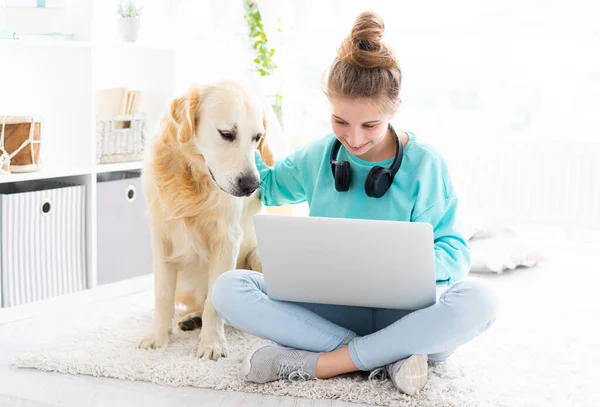 Nettes Mädchen mit Hund arbeitet am Laptop — Stockfoto