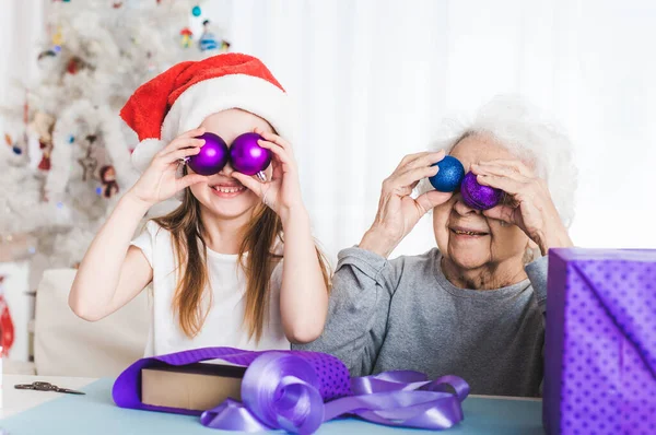 Nieta sosteniendo bolas decorativas con la abuela — Foto de Stock