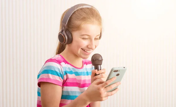 Meisje met telefoon in de ene hand en microfoon in de andere — Stockfoto
