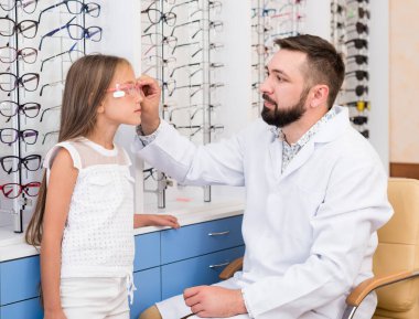 Kız ve doktor gözlük seçiyor.