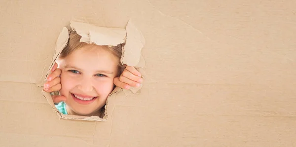 Mała dziewczynka patrząca z dziury w tekturze — Zdjęcie stockowe
