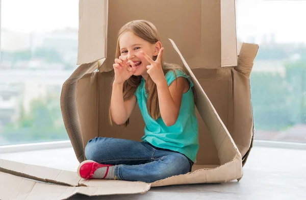 Liten flicka gör narr i pappkartong — Stockfoto