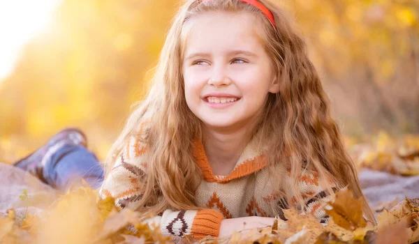 Kind liegt auf Herbstblättern — Stockfoto