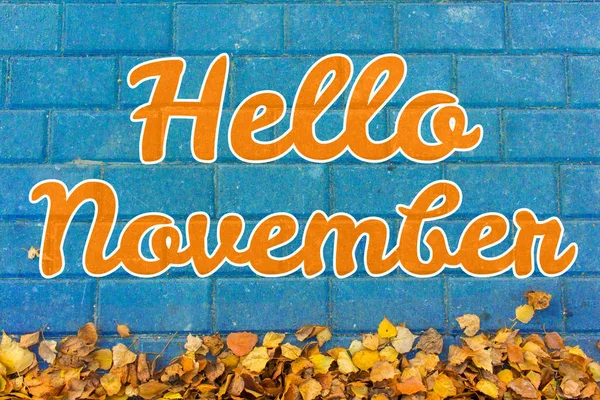 Hola, letras de noviembre. Concepto de otoño. Hojas amarillas sobre adoquín azul — Foto de Stock