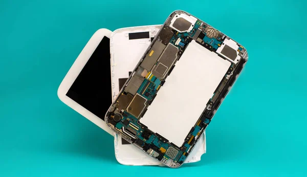 Tablet repair. Close-up disassembled mobile phone parts. Colorful blue background.