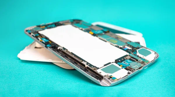 Tablet repair. Close-up disassembled mobile phone parts. Colorful blue background.