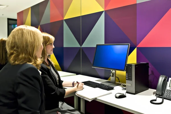 Trabalhadores em uma sala de informática olhando para um monitor — Fotografia de Stock