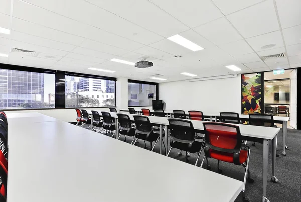 Moderner Konferenzsaal mit Stühlen und langen Tischen — Stockfoto