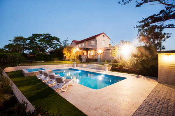 Дом и сад с бассейном освещают огни — стоковое фото