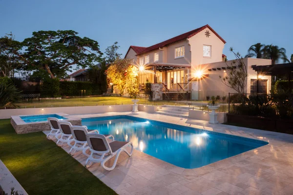 Moderna piscina con una gran casa iluminada con luces — Foto de Stock