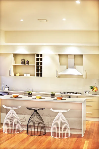 Kitchen with polished wooden floor  and chairs beside the counte