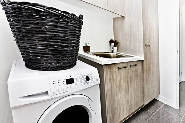 stock image Modern laundry room with a washing machine and basket 