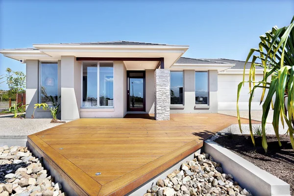 Patio de madera con grandes rocas alrededor de una mansión moderna — Foto de Stock