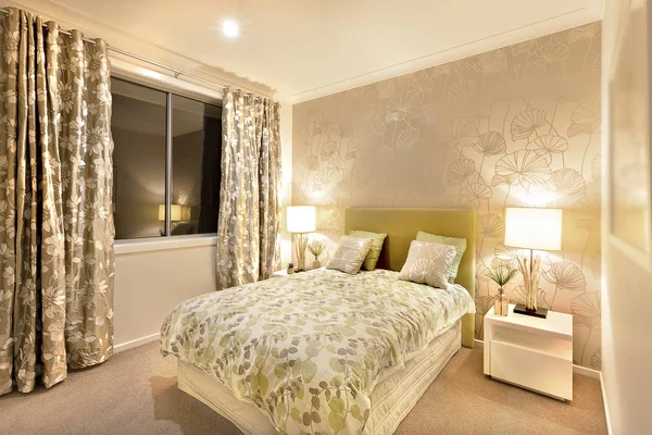 Современная спальня с двуспальной кроватью освещается настольными лампами — стоковое фото
