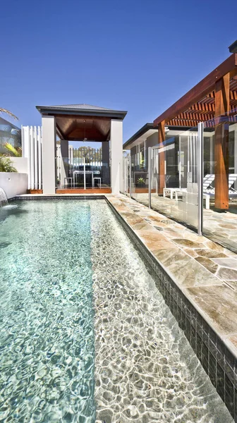 Piscina moderna com área de pátio exterior e pilares de madeira — Fotografia de Stock