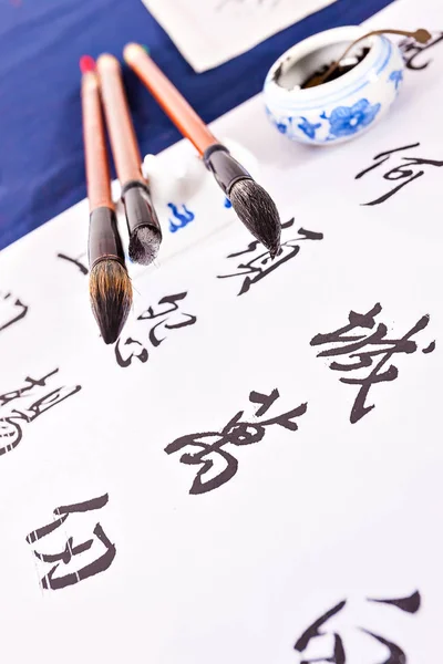 Paint brushes on a white paper which has Chinese letters Stock Photo