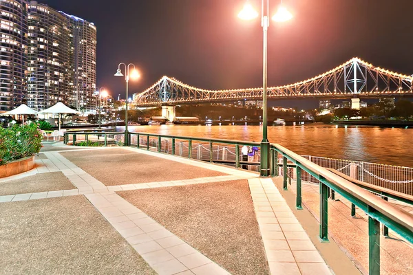 Bord de l'eau au bord d'une rivière la nuit avec un long pont — Photo