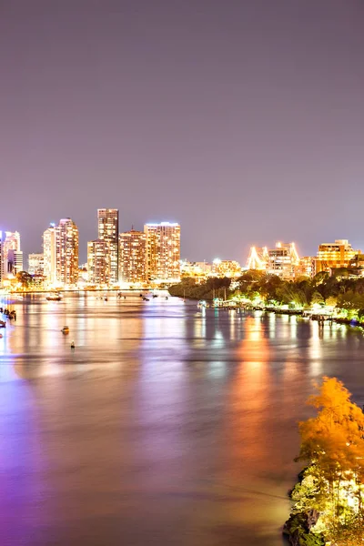 Foto de la ciudad nocturna con luces brillantes iluminadoras junto a un río — Foto de Stock