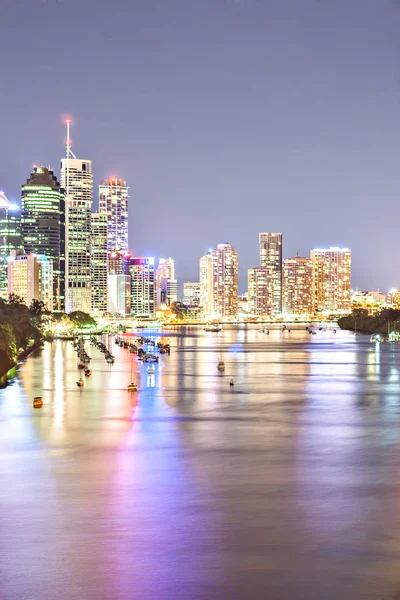 Céu de cidade noturno com luzes brilhantes iluminando atrás de um rio — Fotografia de Stock