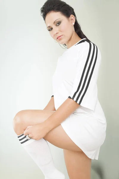 Pretty brunette putting on white soccer socks — Stock Photo, Image