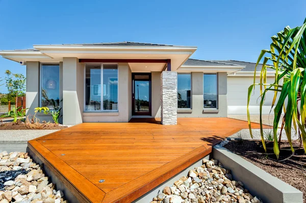 Patio de madera con grandes rocas alrededor de una mansión moderna — Foto de Stock