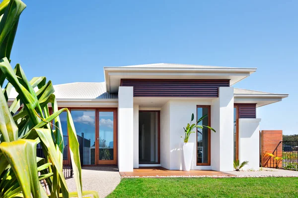 Moderne villa met een grasveld in de buurt van een lang blad boom en blauwe hemel — Stockfoto