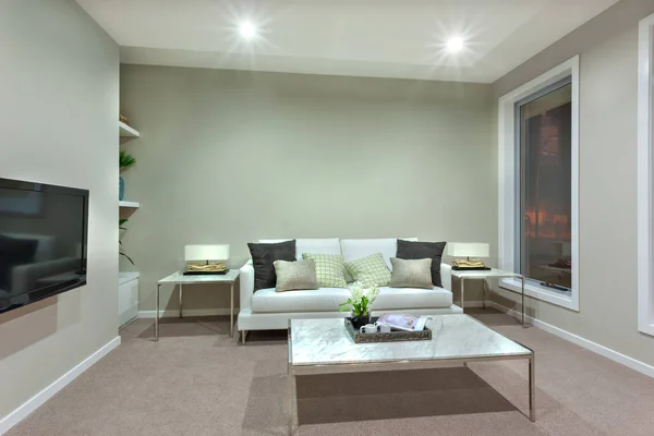 Una sala de estar con una pequeña mesa blanca y almohadas en el sofá — Foto de Stock