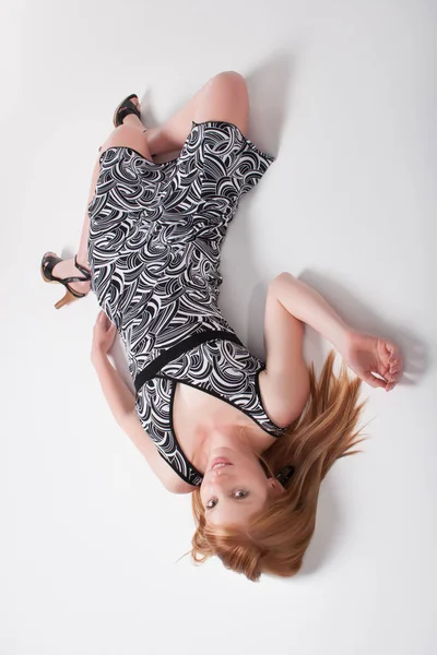 Model in a monochrome dress lying in a studio — Stock Photo, Image