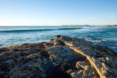 Okyanus dalgaları Currumbin, Gold Coast, Avustralya 'nın kayalık kıyılarına çarpıyor.