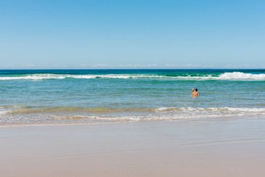 Yaz tatilleri, aile zamanları. Babası oğluna Avustralya sahillerinde yüzmeyi öğretiyor, Byron Bay.
