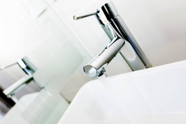 Beyaz lavaboda modern bir krom musluğu.