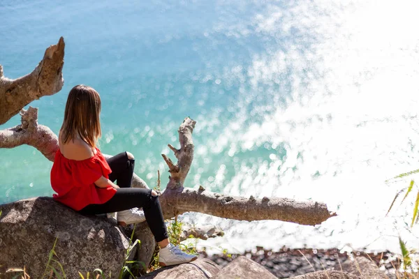 Uma jovem mulher bonita sentada na rocha sobre a praia — Fotografia de Stock