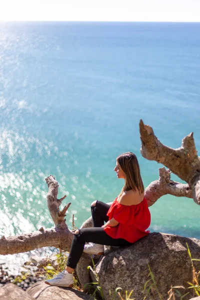 Uma jovem mulher bonita sentada na rocha sobre a praia — Fotografia de Stock