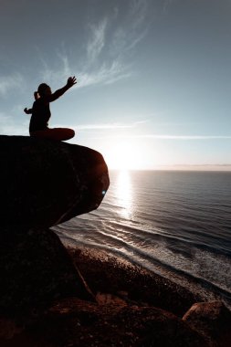 Rock 'ta yoga yapan genç bir kadın.