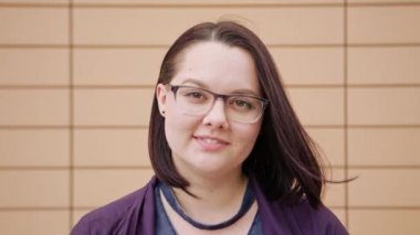 Bej renkli bir arka planda gülümseyen genç bayan