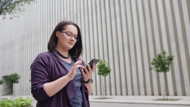 Jovem senhora usando óculos usando telefone na cidade — Vídeo de Stock