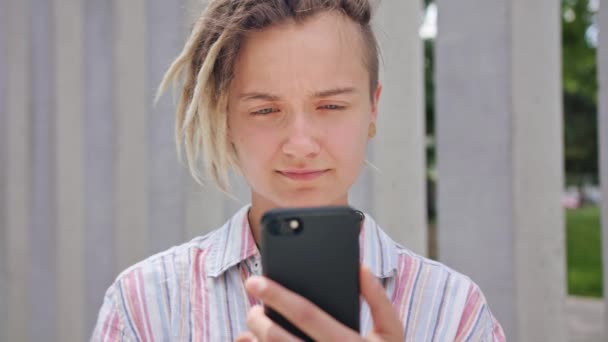 Joven dama con peinado moderno usando el teléfono en la ciudad — Vídeos de Stock