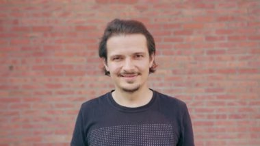Bir tuğla duvar arka planda gülümseyen genç adam