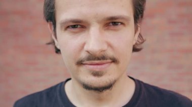 Bir tuğla duvar arka planda gülümseyen genç adam