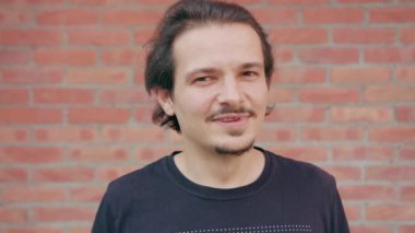 Bir tuğla duvar arka planda gülümseyen genç adam