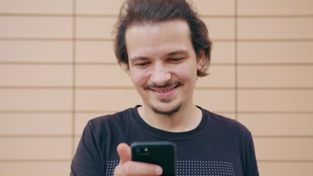 Молодой человек использует телефон на открытом воздухе — стоковое видео