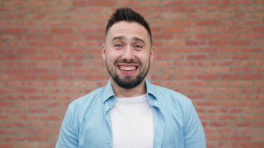 Sakallı bir tuğla duvara gülümseyen