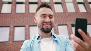 Sakallı bir tuğla bina karşı bir telefonu kullanarak