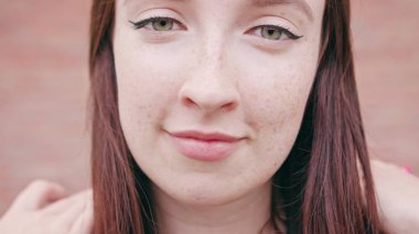 Mutlu gülen esmer kadın saçlarını okşayarak