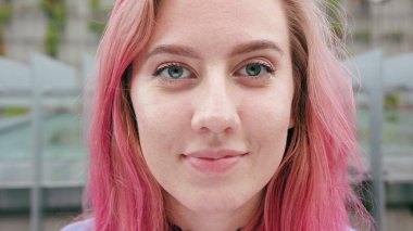 Şehirdeki pembe saçlı mutlu gülümseyen kadın