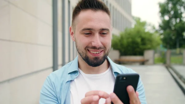 Hombre con barba usando un teléfono en la ciudad — Foto de Stock