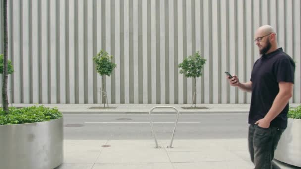 Человек в очках с бородой, использующий телефон в городе — стоковое видео